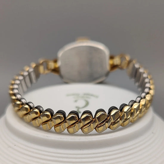 Montre vintage Benrus Cocktail Watch 1955, cadran champagne, mouvement manuel, sur fond. Élégante montre femme.