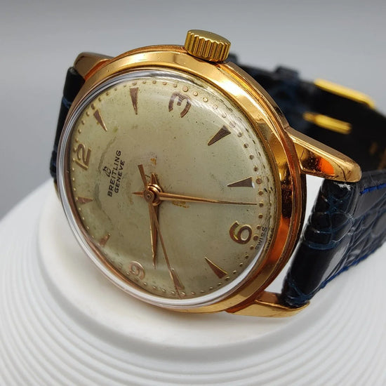 Vue macro de la couronne d'une montre Breitling Genève vintage de 1955. Détail du mouvement manuel et cadran champagne.