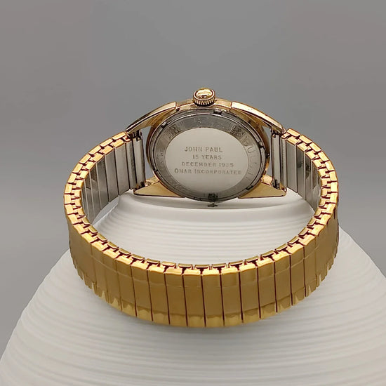 Montre automatique vintage Bulova 23 Jewels Self-Winding (1955) sur fond. Cadran champagne/crème, mouvement automatique.