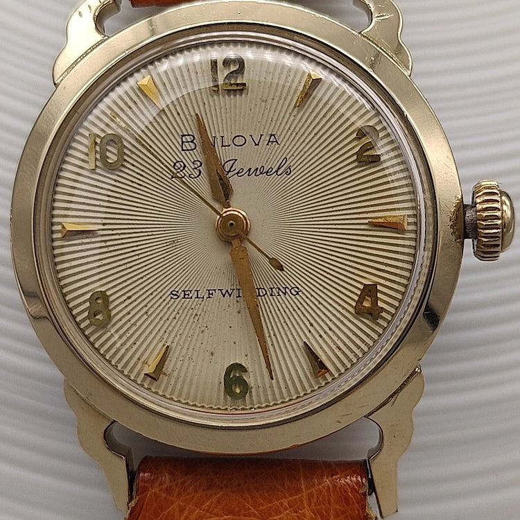 Montre vintage Bulova Selfwinding 23 Jewels 1957, mouvement automatique, vue détaillée du verre champagne.