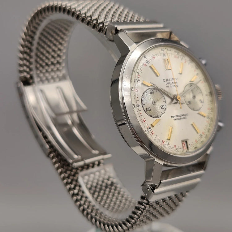 Couronne détaillée d'une montre vintage Cauny Prima Chronographe 1955, mouvement manuel, cadran argenté.
