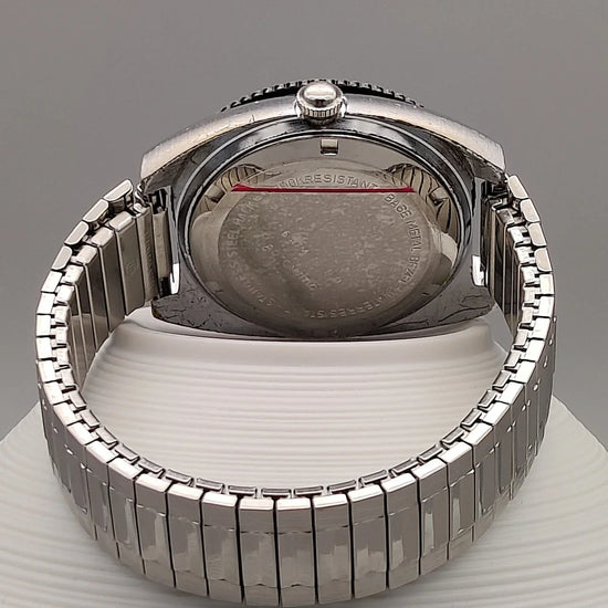 Montre vintage automatique Clinton World Timer 1972, cadran noir, mise en scène sur fond élégant.