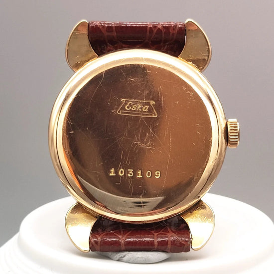 Montre vintage Eska Fab. Suisse 1950 sur fond élégant. Cadran crème/champagne, mouvement manuel. Authentique montre suisse de collection.