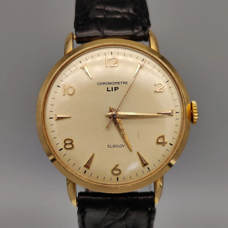 Montre Lip Chronometre vintage 1955, cadran champagne. Gros plan détaillé du verre, excellent état.
