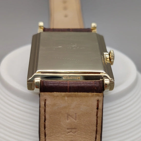 Montre Longines Vintage Square 1955, cadran champagne, mouvement manuel, sur fond élégant.