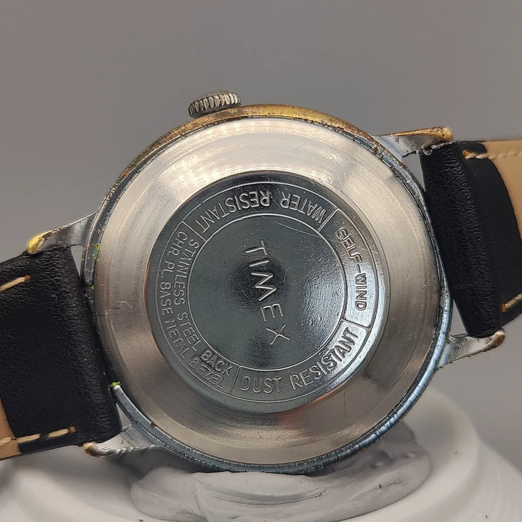 Montre automatique vintage Timex Automatic Water Resistant de 1973, cadran champagne, en photo de fond.